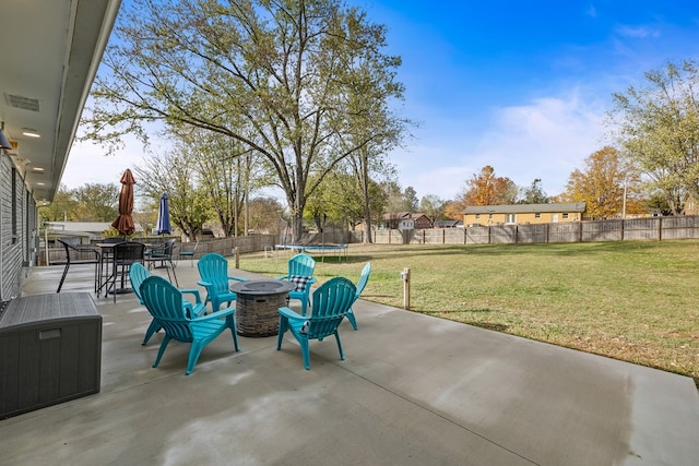 view of patio featuring an outdoor fire pit, a trampoline, outdoor dining space, and a fenced backyard