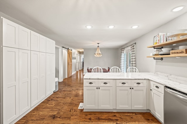 kitchen with open shelves, hanging light fixtures, stainless steel dishwasher, a barn door, and white cabinets