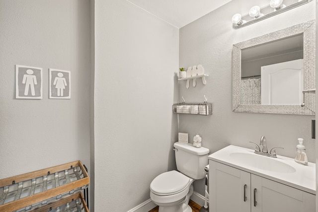 bathroom with toilet, baseboards, and vanity