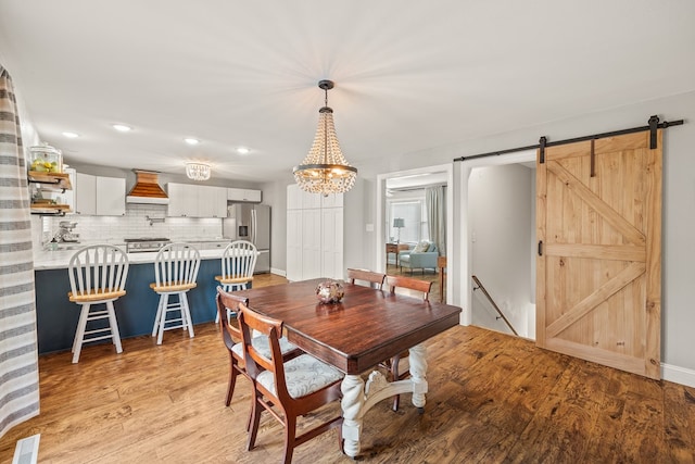 dining space with a barn door, light wood-style flooring, visible vents, and recessed lighting