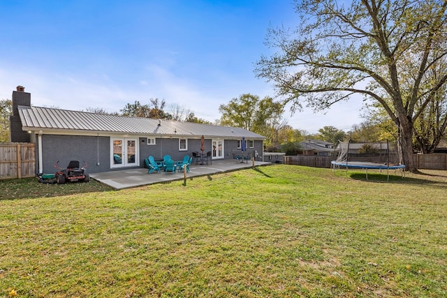 back of property featuring metal roof, a trampoline, a patio area, and a fenced backyard