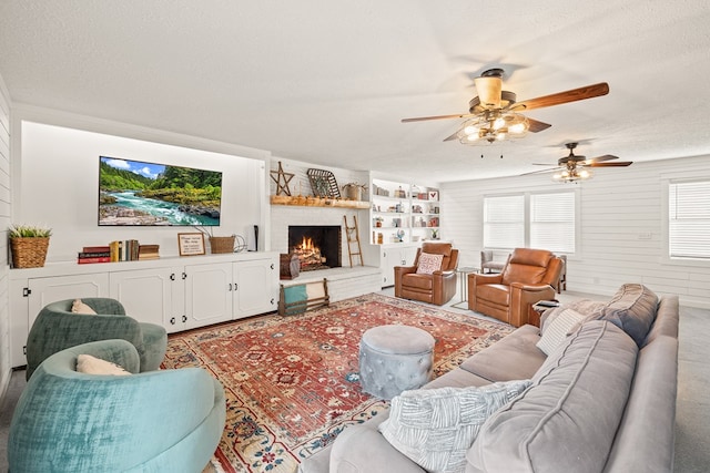 living area with a textured ceiling, a large fireplace, built in features, and wooden walls