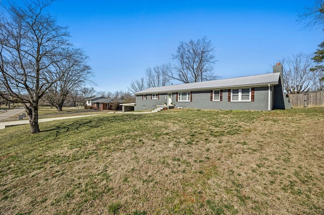 ranch-style house with brick siding, a chimney, metal roof, and a front yard