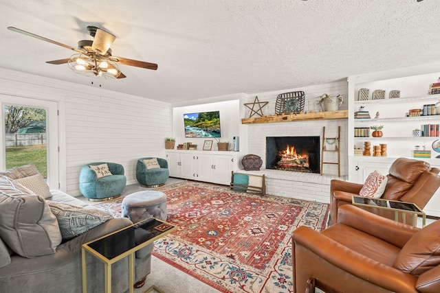 living area with a brick fireplace, ceiling fan, and a textured ceiling