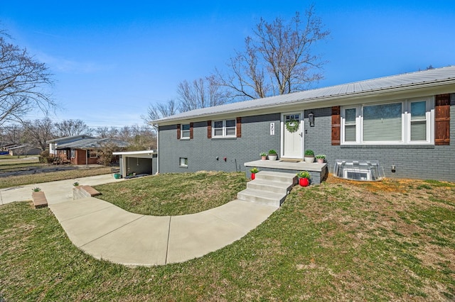 ranch-style home with brick siding, metal roof, and a front lawn