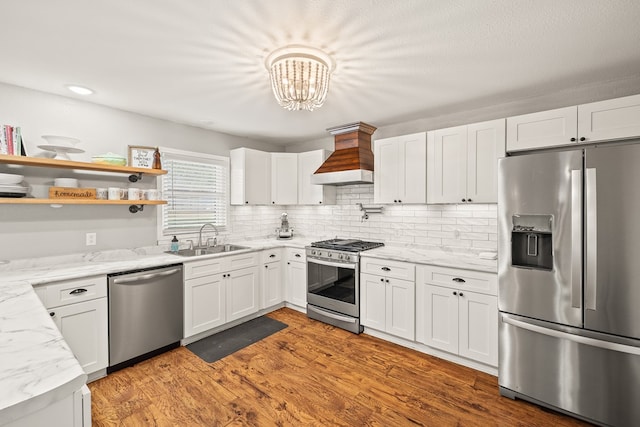 kitchen featuring white cabinetry, custom range hood, appliances with stainless steel finishes, and a sink