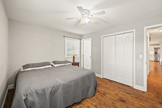 bedroom featuring a closet, baseboards, stainless steel refrigerator with ice dispenser, and dark wood-style flooring