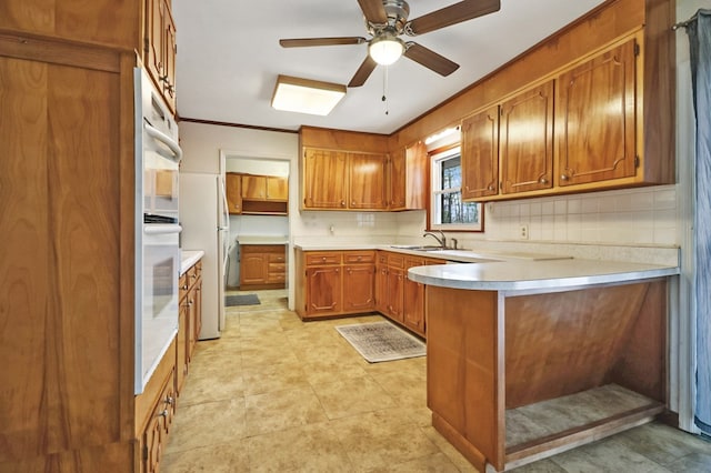 kitchen with light countertops, brown cabinetry, a peninsula, and decorative backsplash