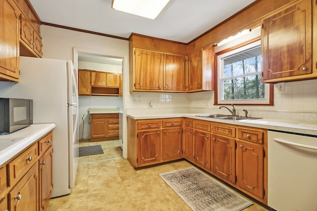 kitchen featuring brown cabinetry, white appliances, light countertops, and a sink