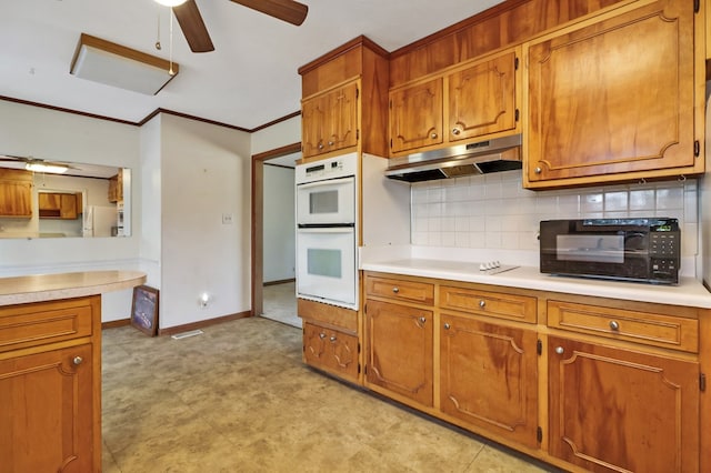 kitchen with white double oven, under cabinet range hood, light countertops, ornamental molding, and brown cabinets