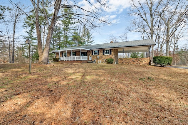 ranch-style home with brick siding, a chimney, a porch, a front yard, and an attached carport