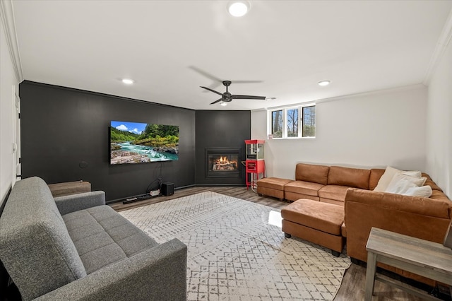 living area featuring recessed lighting, ornamental molding, a glass covered fireplace, a ceiling fan, and wood finished floors