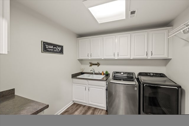 clothes washing area featuring cabinet space, visible vents, dark wood-style floors, washing machine and dryer, and a sink