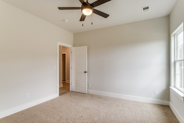 empty room with a healthy amount of sunlight, carpet, visible vents, and baseboards