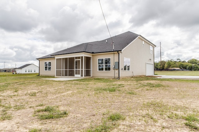 rear view of property featuring roof with shingles, a yard, a patio, an attached garage, and a sunroom