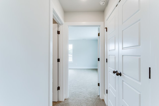 hallway featuring baseboards and light colored carpet