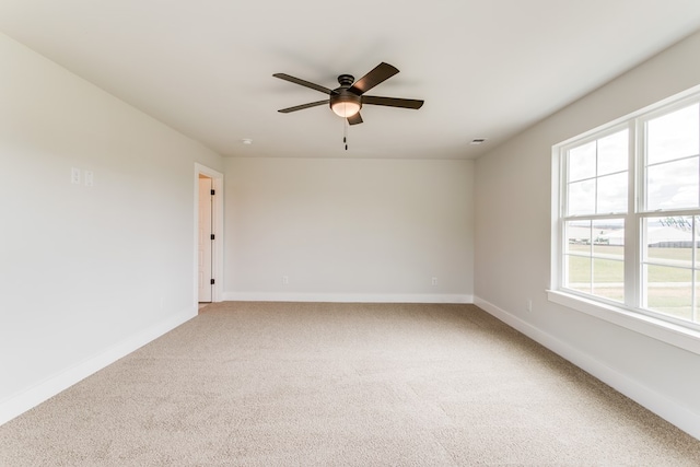 carpeted spare room featuring baseboards and a ceiling fan