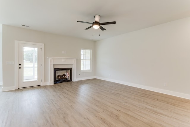 unfurnished living room with baseboards, a fireplace, visible vents, and light wood-style floors