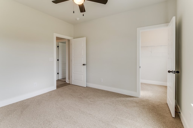 empty room featuring baseboards, ceiling fan, and light colored carpet