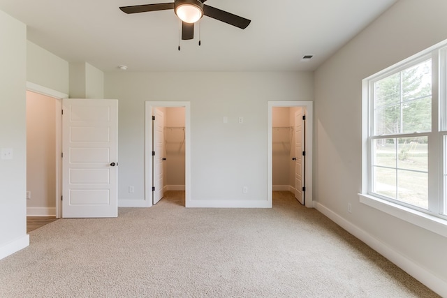 unfurnished bedroom with visible vents, light carpet, a spacious closet, and baseboards