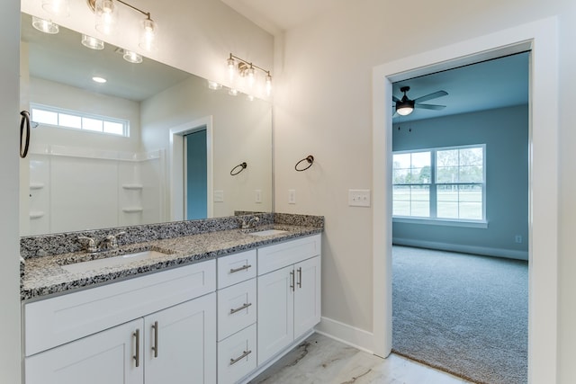 full bath featuring double vanity, a sink, a ceiling fan, and baseboards