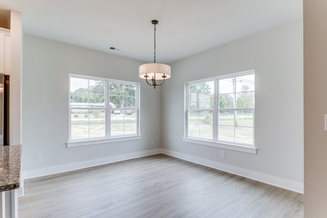 unfurnished dining area featuring baseboards, visible vents, and light wood-style flooring