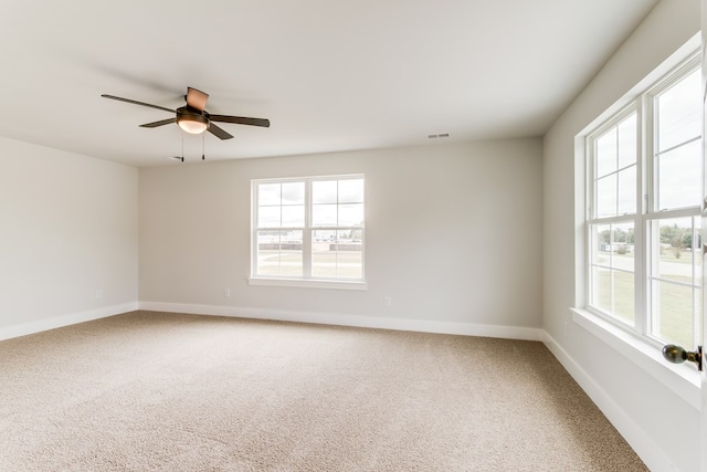 empty room with carpet floors, visible vents, baseboards, and a wealth of natural light