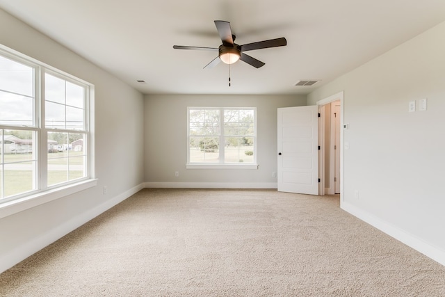 empty room featuring light colored carpet, visible vents, ceiling fan, and baseboards