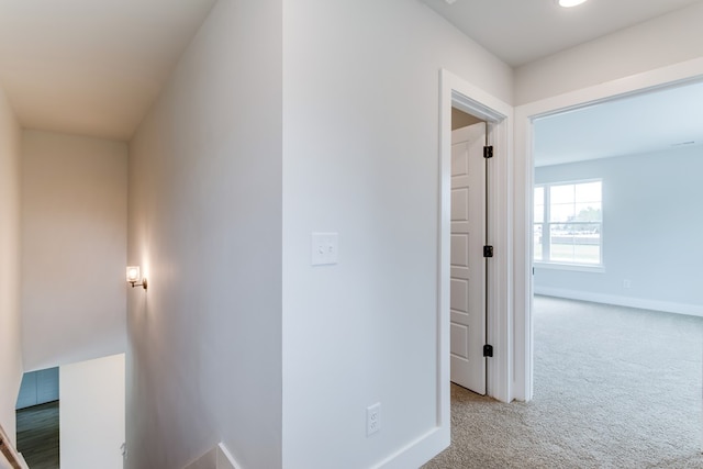 hallway with carpet flooring and baseboards