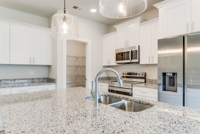 kitchen with decorative light fixtures, visible vents, appliances with stainless steel finishes, white cabinets, and a sink