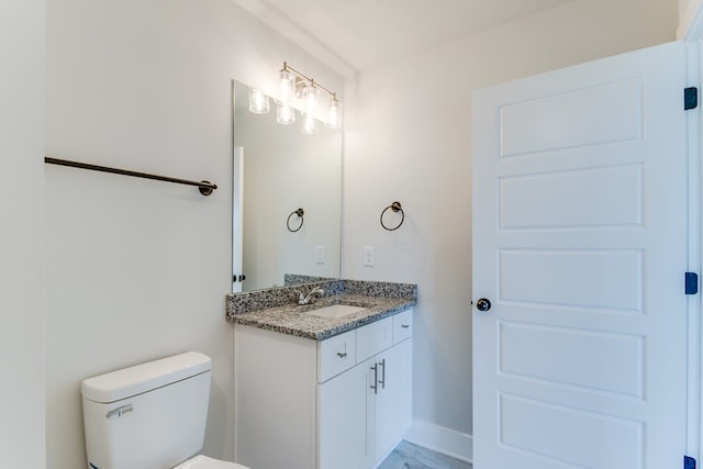 half bath with toilet, vanity, and baseboards