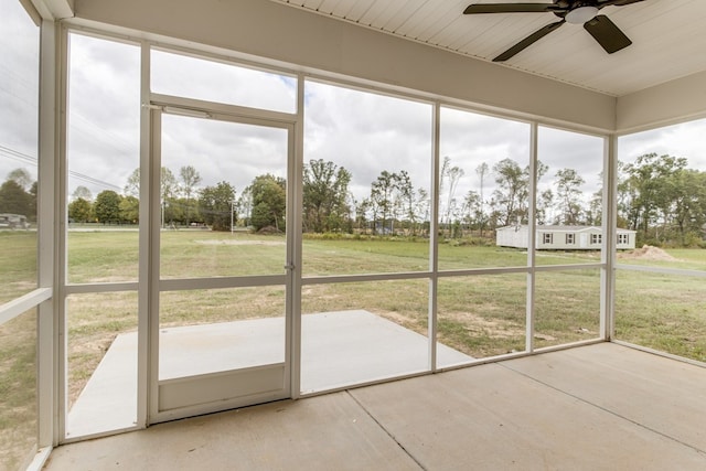 unfurnished sunroom featuring a ceiling fan and a healthy amount of sunlight