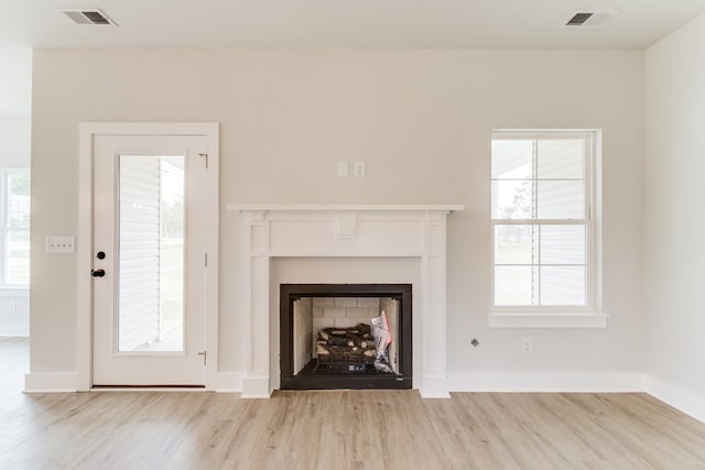 unfurnished living room featuring light wood-style flooring, a fireplace, visible vents, and baseboards