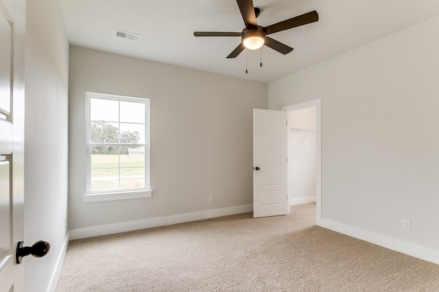 unfurnished bedroom with a ceiling fan, light colored carpet, visible vents, and baseboards