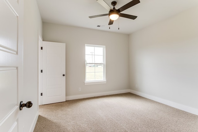 carpeted spare room featuring ceiling fan, visible vents, and baseboards