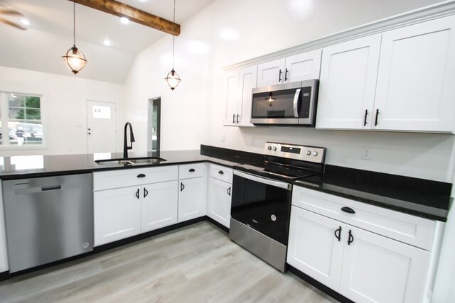 kitchen featuring appliances with stainless steel finishes, dark countertops, white cabinets, and decorative light fixtures