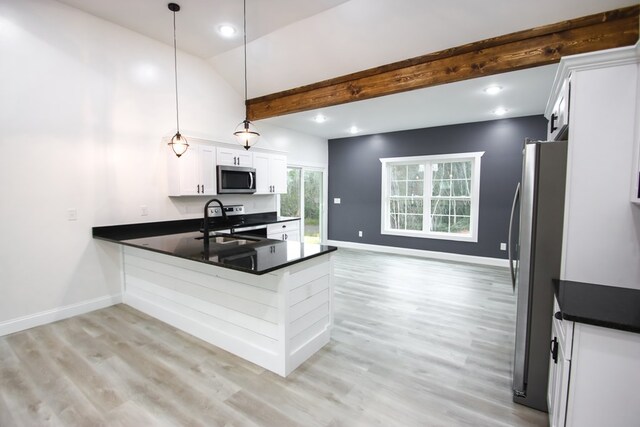 kitchen with dark countertops, hanging light fixtures, appliances with stainless steel finishes, white cabinetry, and a sink