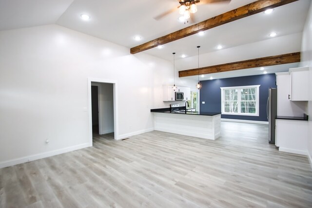 kitchen with dark countertops, white cabinetry, open floor plan, and hanging light fixtures