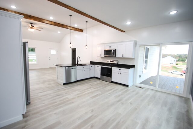 kitchen with white cabinets, dark countertops, appliances with stainless steel finishes, a peninsula, and pendant lighting