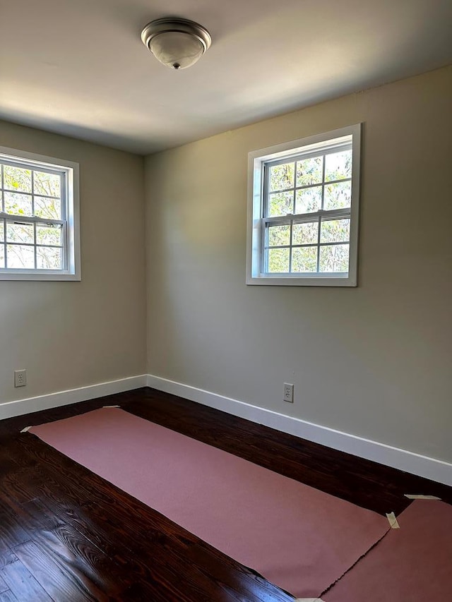 spare room featuring baseboards and wood finished floors