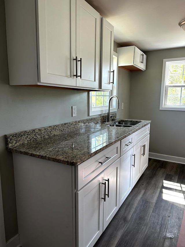 kitchen with dark stone counters, white cabinets, and a sink