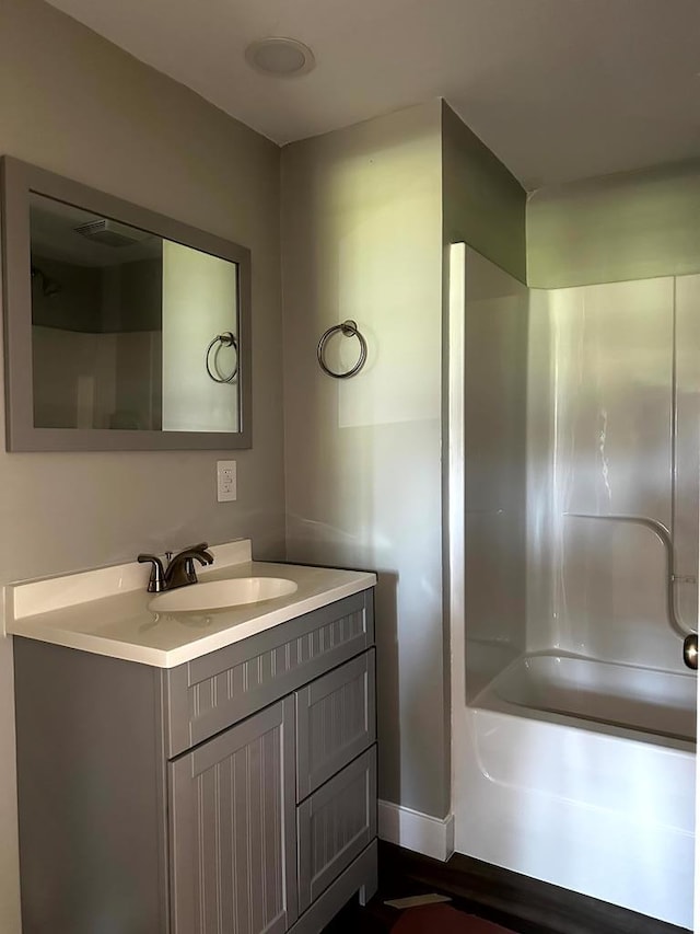 bathroom featuring washtub / shower combination, baseboards, and vanity