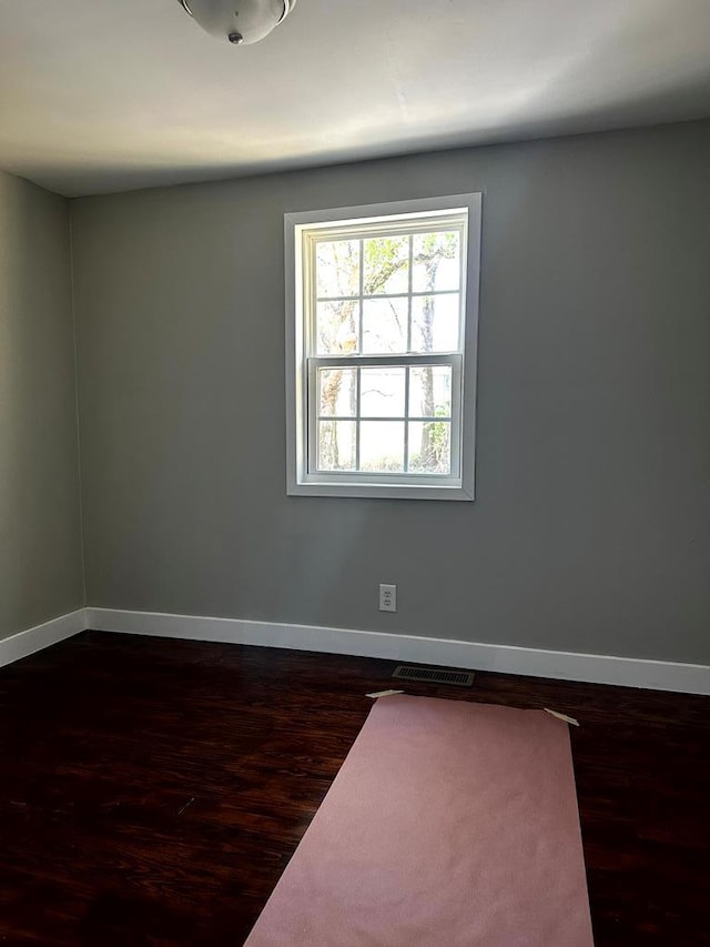 unfurnished room with dark wood finished floors and baseboards