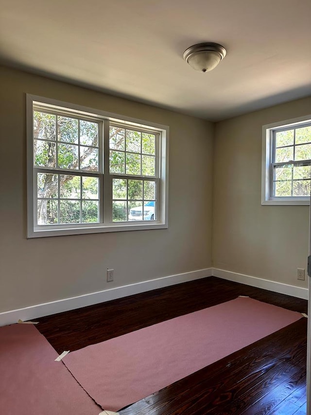 spare room featuring dark wood finished floors and baseboards