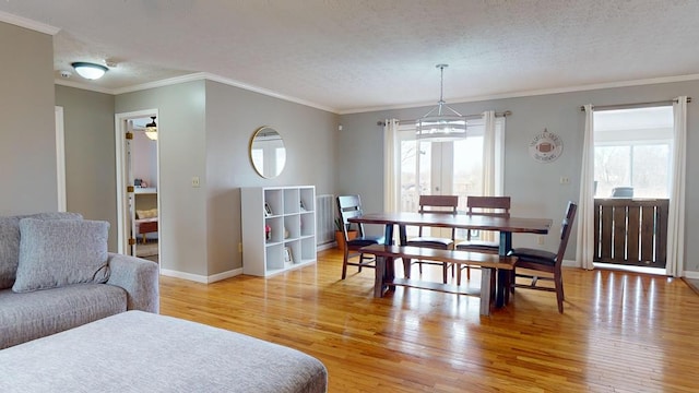 dining room featuring ornamental molding, a textured ceiling, baseboards, and wood finished floors