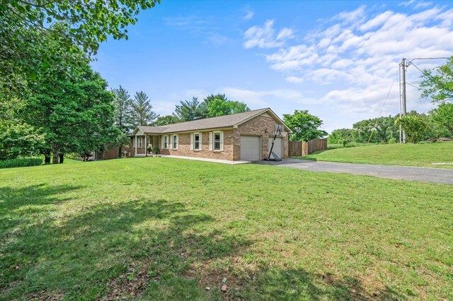 single story home with aphalt driveway, an attached garage, brick siding, and a front yard