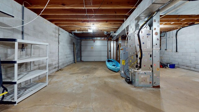 garage with heating unit, concrete block wall, and electric water heater