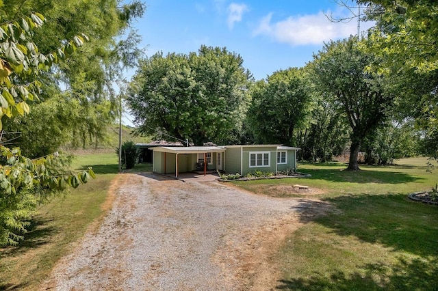 view of front of home featuring dirt driveway, an attached carport, and a front lawn