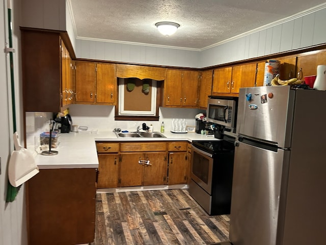 kitchen featuring appliances with stainless steel finishes, light countertops, a sink, and ornamental molding