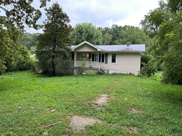 view of front of house featuring covered porch, metal roof, and a front lawn